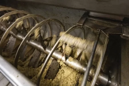 Olive paste being mixed during mechanical extraction process.